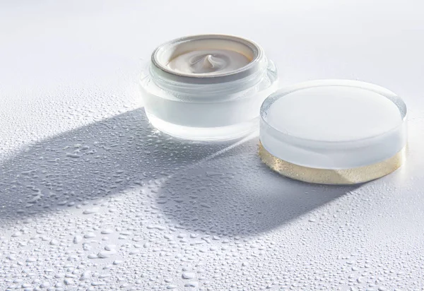El frasco de crema hidratante cosmética sobre el fondo blanco con gotas de agua alrededor del frasco Fotos de stock