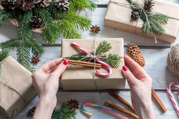 Woman decorating gift box on wooden background. Christmas style — Stock Photo, Image