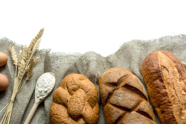 Различные хлеба, пшеницы, ложки наполненной муки, яйца изолированы на белом — стоковое фото