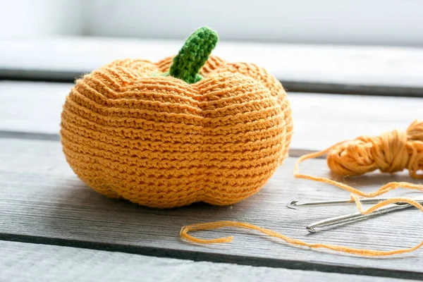 Fond d'Halloween avec citrouille tricotée, crochets et fil orange Photo De Stock