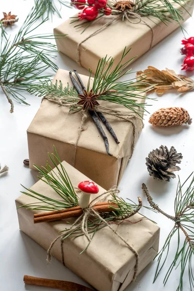 Предпосылки для Рождества и Нового года с обернутыми подарками украшены сосновые ветви, шишки, анисовые звезды и ванильные палочки Стоковое Изображение