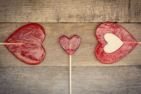 Trois sucettes en forme de coeur sur fond de bois. Concept d'amour. Saint Valentin Image En Vente