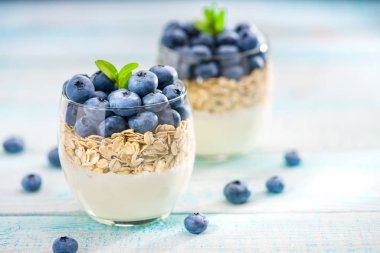 Yoğurt ile yaban mersini ve yulaf ezmesi üzerine ahşap üzerinde net kavanoz