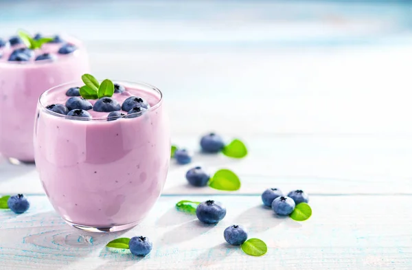 Two glasses of blueberry smoothie on a turquoise wooden backgrou — Stock Photo, Image