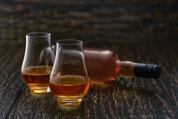 Two glasses of whiskey and  full bottle whiskey on a wooden tabl — Stock Photo, Image