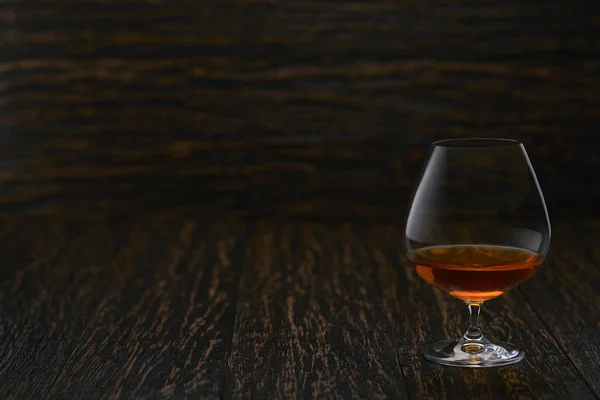 Full glass of cognac on a wooden table, selective focus with cop — 스톡 사진