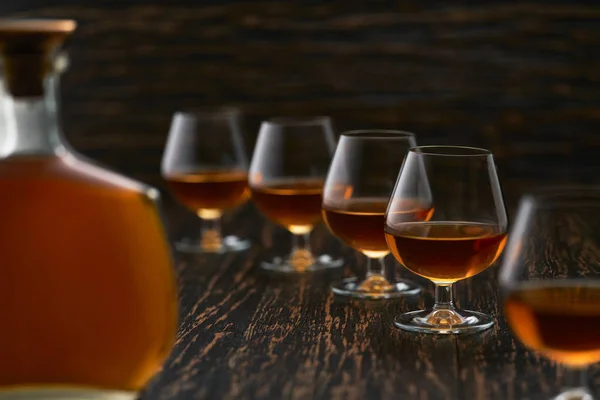 Glasses of cognac on a wooden table with the silhouette of a bot — 스톡 사진