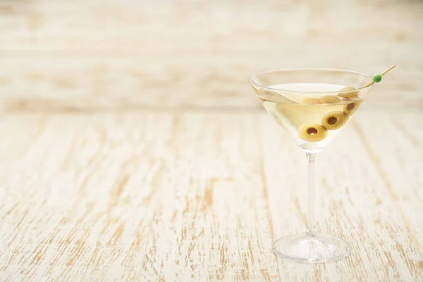 Martini seco clásico con aceitunas verdes sobre fondo de madera blanca — Foto de Stock