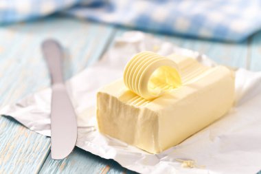 Mavi ahşap bir masa üzerinde bir parça tereyağı, seçici odak.