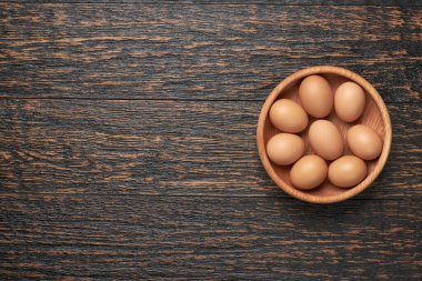 Tahta bir kasede taze tavuk yumurtaları. Siyah tahta bir masanın üstünde..