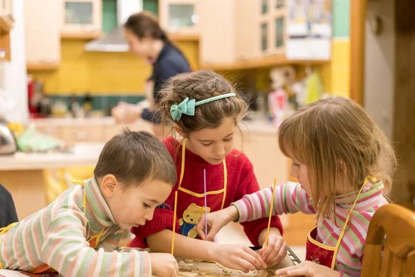 Drei Kinder backen Teigkekse. das Konzept der Teamarbeit und einer glücklichen Familie. — Stockfoto