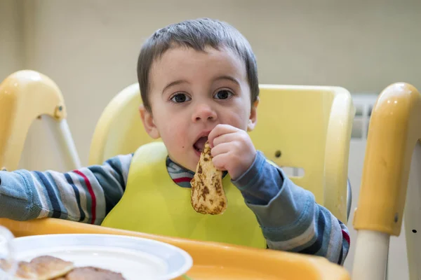 El chico de 2 años está comiendo un panqueque. — Foto de Stock