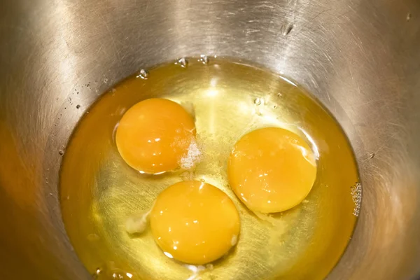 Три яйца в железной чаше, посыпанной солью — стоковое фото