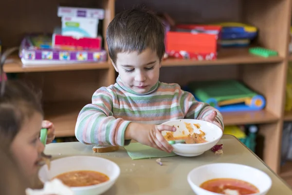Un niño a la edad de 5 años comiendo sopa en el jardín de infantes . — Foto de Stock