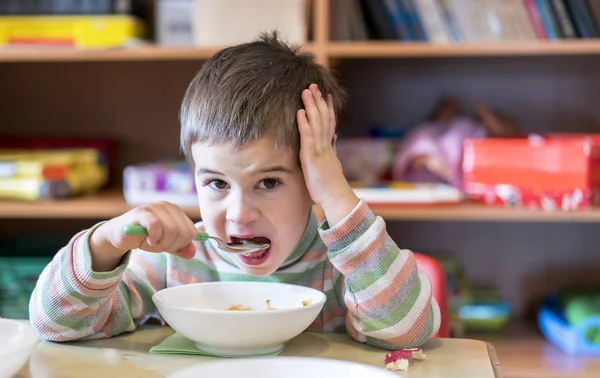 Un niño a la edad de 4 años comiendo sopa en el jardín de infantes . — Foto de Stock