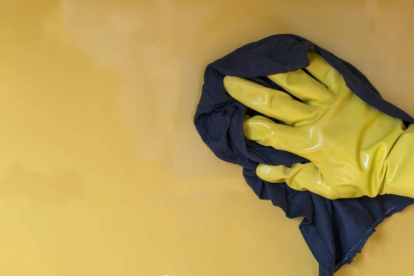 Een gele handschoen hand veegt de gele muur. Het begrip reinheid — Stockfoto