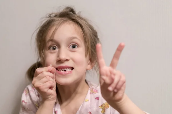 A little girl had a milk tooth. She holds it in her hand — Stock Photo, Image