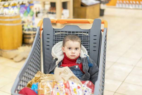 Тележка с продуктами, в которых сидит ребенок — стоковое фото