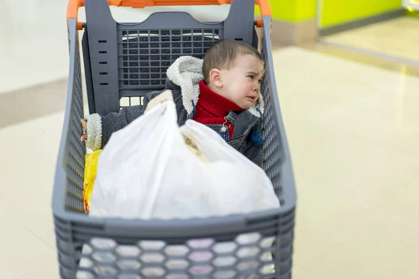 Хлопчик плаче в супермаркеті у візку. Забута дитина — стокове фото