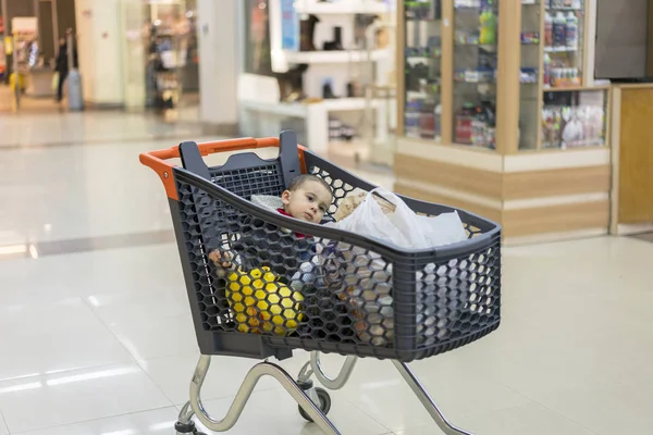 Um carrinho com produtos em que a criança se senta — Fotografia de Stock