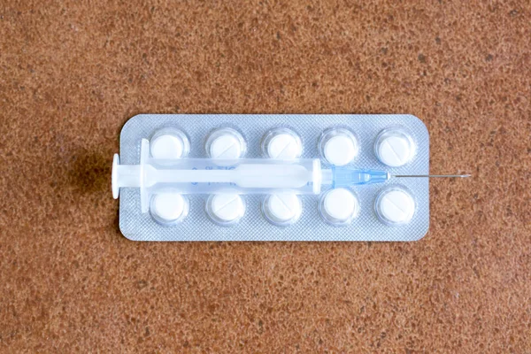 Tabletler ve kahverengi bir arka plan üzerinde şırınga — Stok fotoğraf