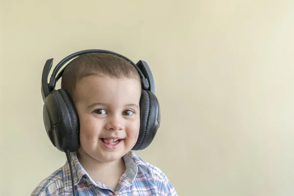 Piękne chłopca w duże słuchawki. Chłopiec w plaid shirt, słuchanie muzyki — Zdjęcie stockowe