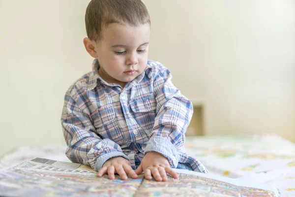 Un niño hermoso está mirando un libro grande —  Fotos de Stock