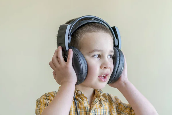 4-letni chłopiec w koszuli uważnie słucha muzyki w duże słuchawki Czarny — Zdjęcie stockowe