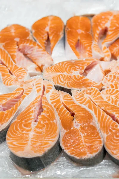 魚市場で鮭赤魚のステーキ。背景として魚のサーモンの生の新鮮なステーキ。ノルウェー サーモンのムニエル氷の大規模な山。販売のため並んでサーモンの大きな有機ステーキ. — ストック写真