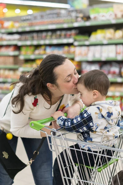 Счастливая мать обнимает и целует сына в магазине — стоковое фото