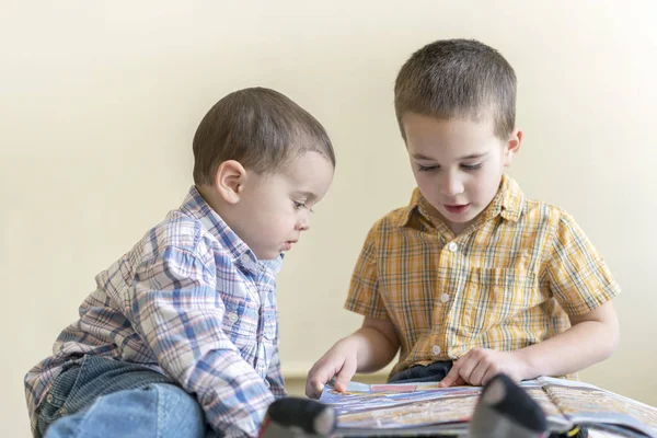 Dos niños lindos están estudiando un libro. Dos niños con camisetas y un libro. concepto de educación . —  Fotos de Stock