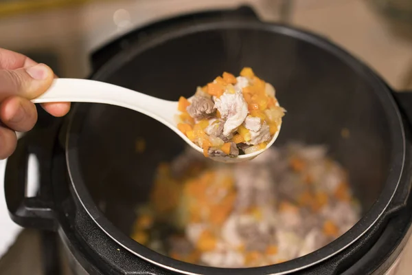 Cooked meat with vegetables in a cooked white spoon on a steam background — Stock Photo, Image