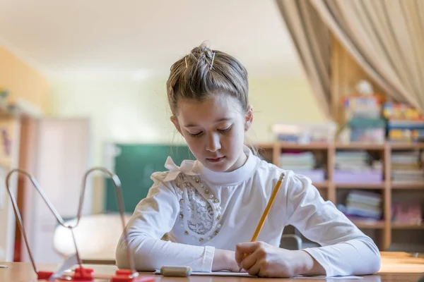Маленька дівчинка за столом пише — стокове фото