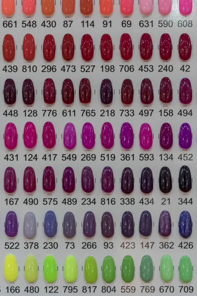 Set of different nail polish colours on palette in cosmetic store. Wide range of nail coloring. — Stock Photo, Image