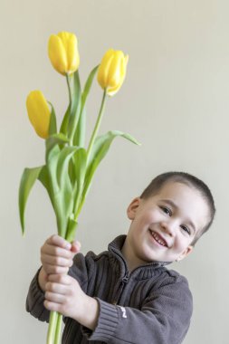 Çocuk elindeki çiçek saklanıyor. Açık renkli. Avrupa görünüm.