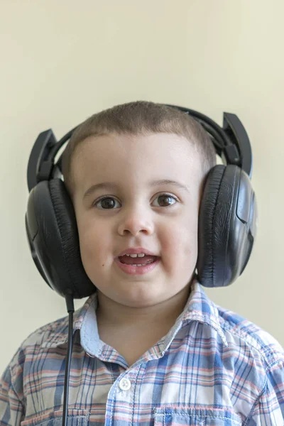 Piękne chłopca w duże słuchawki. Chłopiec w plaid shirt, słuchanie muzyki — Zdjęcie stockowe