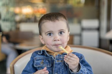 Bir erkek mutlu bebek patates kızartması yiyor. lokanta. Avrupa.