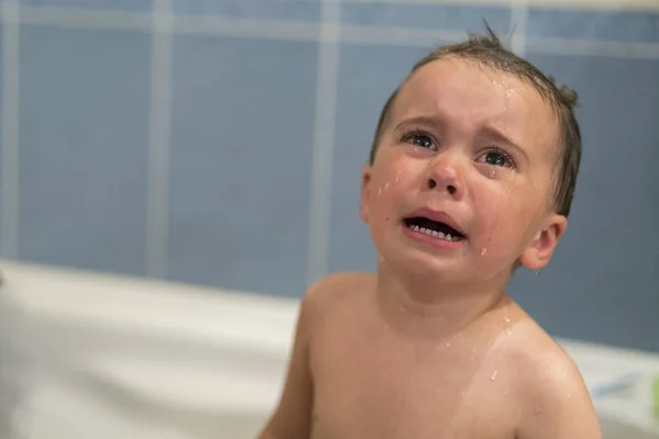 Crying baby by in a bathtub. Infant kid sreaming while taking a bath. baby cries in the bathroom.