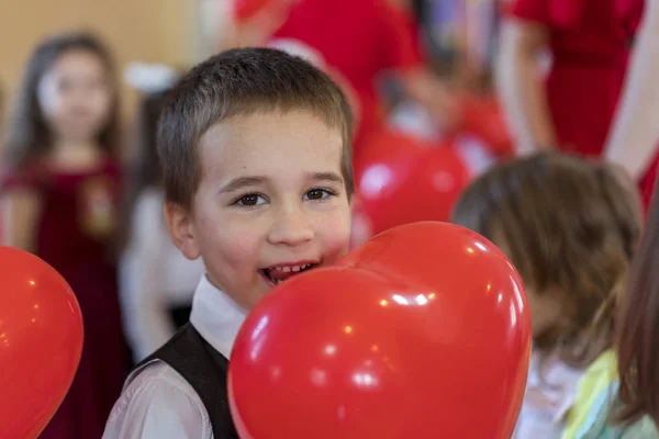 little funny boy with red balloon. portrait of a funny kid holding a big red balloon against an abstract background.