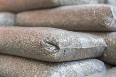 Heap of stacks of Pine pellets - stock image. Eco pellets- biomass in bags. clipart