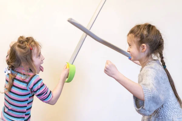 Due ragazze con spade giocattolo giocano a cavalieri. Emozioni da bambini . — Foto Stock