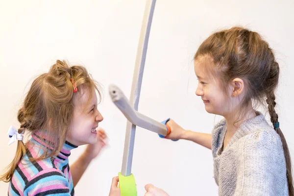 Zwei Mädchen mit Spielzeugschwertern spielen Ritter. deyochki argumentieren und ärgern sich. Konflikt — Stockfoto