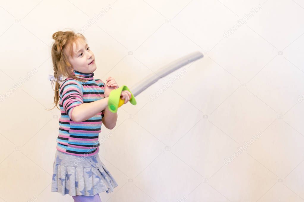 A girl holding a toy sword in her hand. The girl is holding a toy saber. Playing the Knight