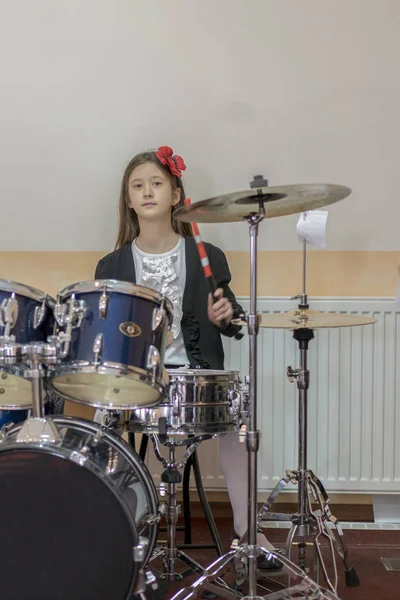 Молодая кавказская девочка-подросток играет на барабанах. Девушка играет на барабанах. Девочка учится играть на барабанах в музыкальной школе — стоковое фото