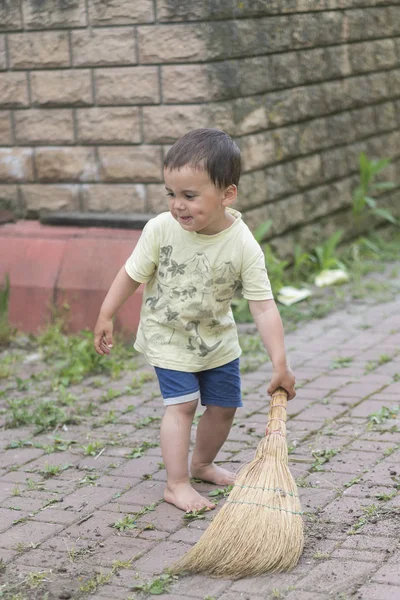 baby boy sweeping the yard. little boy my mother\'s helper, sweeping brush the floor