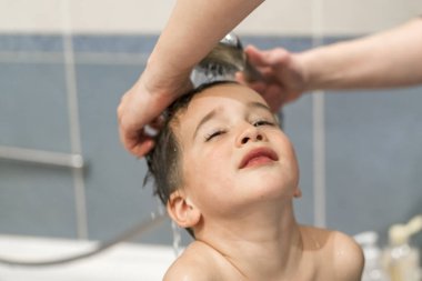 Anne ile bebek duş banyo yıkama. Annemin elleri küçük çocuğun kafasını tuvalete yıkama