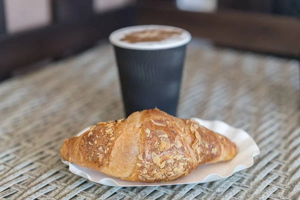 Café para ir em uma xícara de papel com croissants na mesa de madeira,. Café para ir em uma xícara de papel com croissants, perto. foco seletivo — Fotografia de Stock