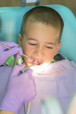 Pediatrik diş hekimi, dişçi koltuğunda küçük çocukların dişlerini muayene ediyor.. 