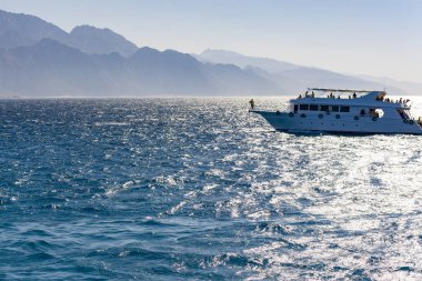 Dağların arkasında beyaz bir yat. Deniz eğlencesi ve turizm kavramı.