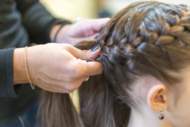 Cropped shot of mother and daughter standing in nightwear while mom making braid for cutie.